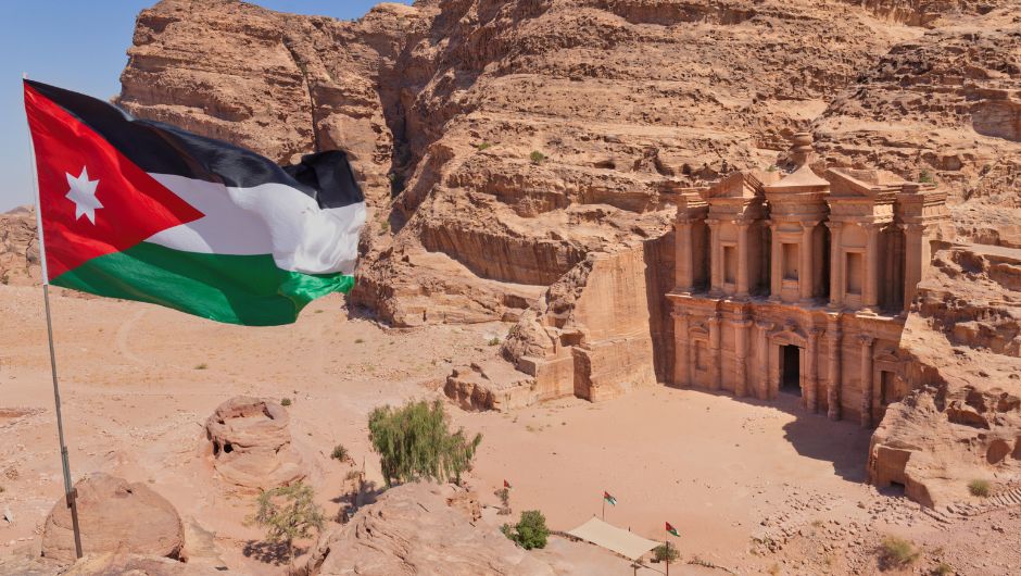 Jordanian flag blowing with The Monastery, Petra in the back ground.