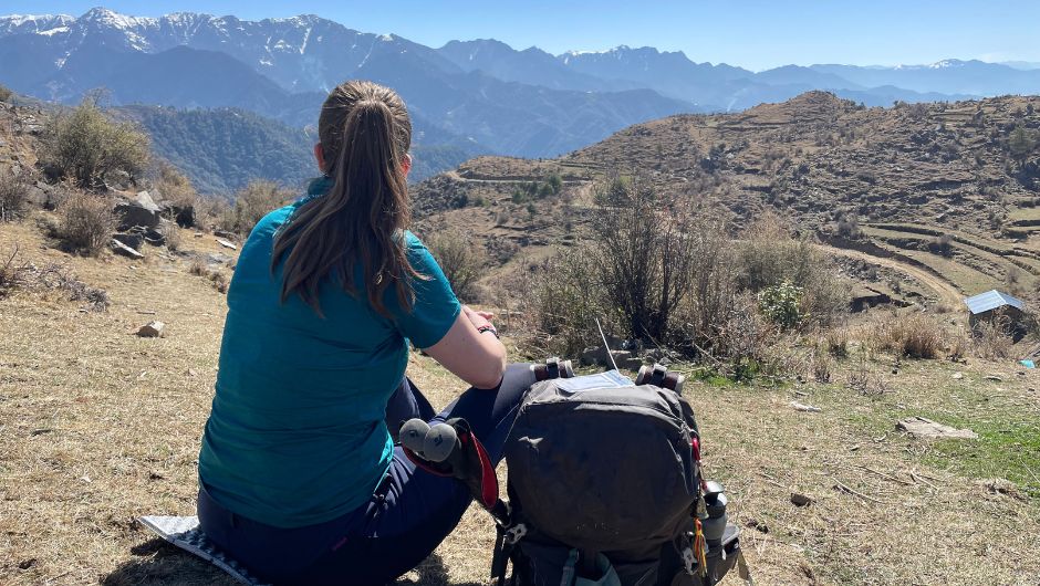 overseas trekker resting next to her day pack and looking at the views