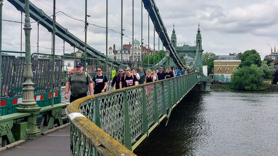 challengers trekking across an old iron bridge on the thames footpath challenge