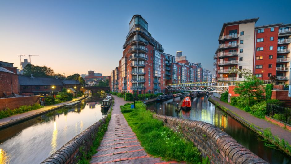 Grand union canal in Birmingham at sunrise with barges and apartment buildings