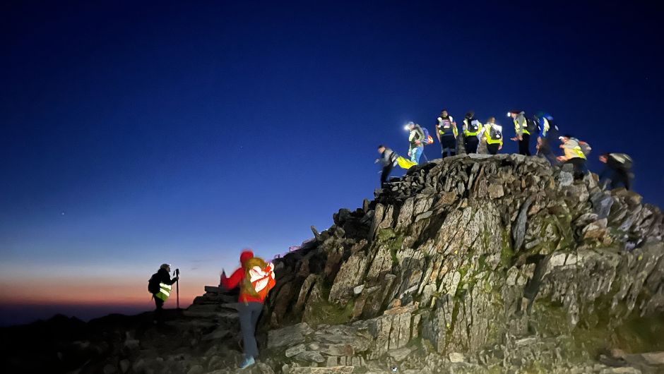 A group of trekkers on the summit of Mt Snowdon, Wales at sunrise
