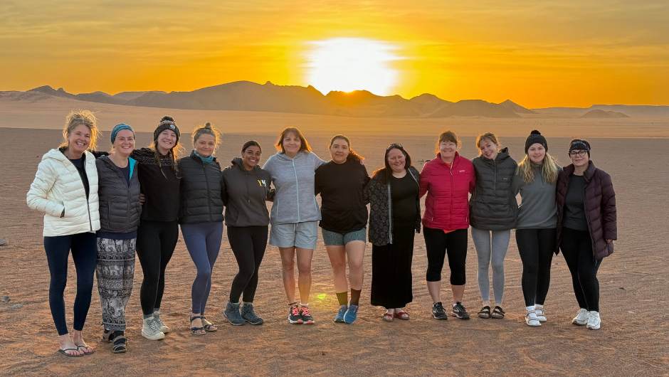 Smiling group of charity challenge participants at sunset in the desert