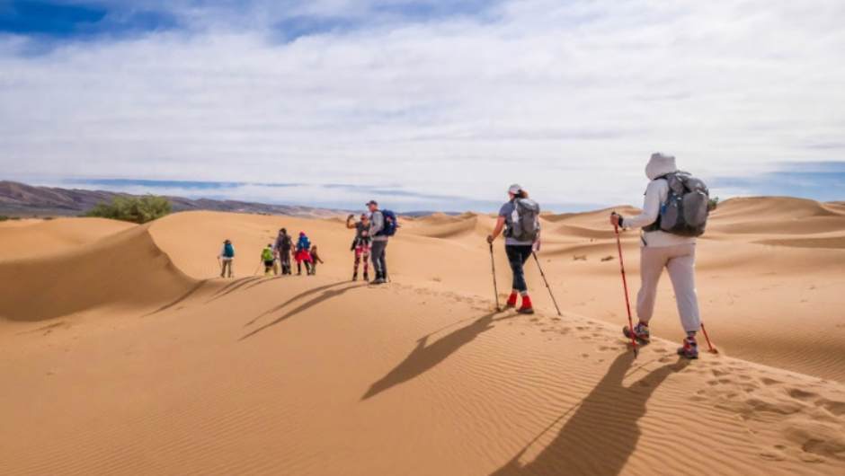 Challengers with daypacks and walking poles on the sahara desert trek with charity challenge