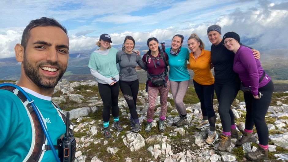 Sameed posing at the summit of a mountain with some charity challenge participants