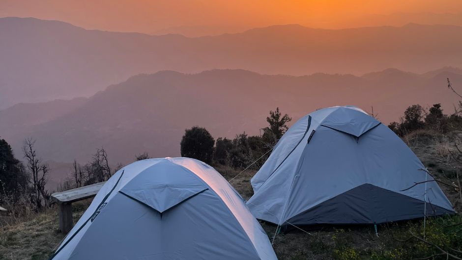 where to start camping. two tents pitched on grass, overlooking hills and a sunset