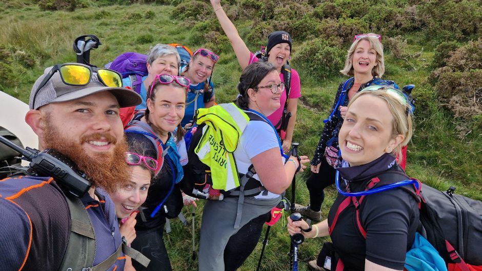 elliot swinney, charity challenge leader, smiling with a group of particiapnts on the coppatrek! with gi brecon beacons challenge
