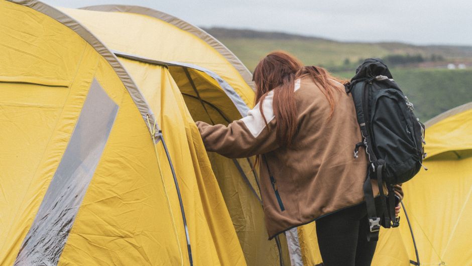 woman stood at the doorway of her tent with a backpack