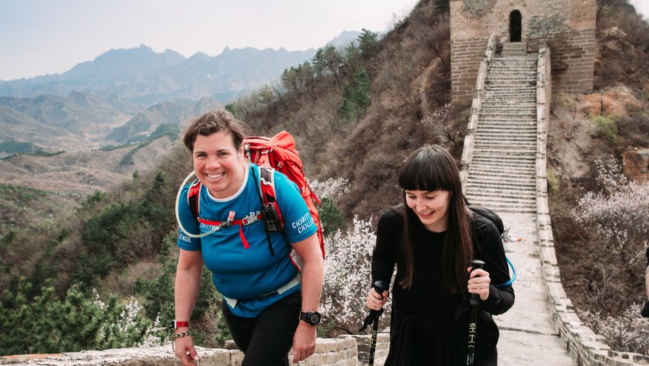 A charity challenge leader and participant walking up some stairs on the Great Wall of China.