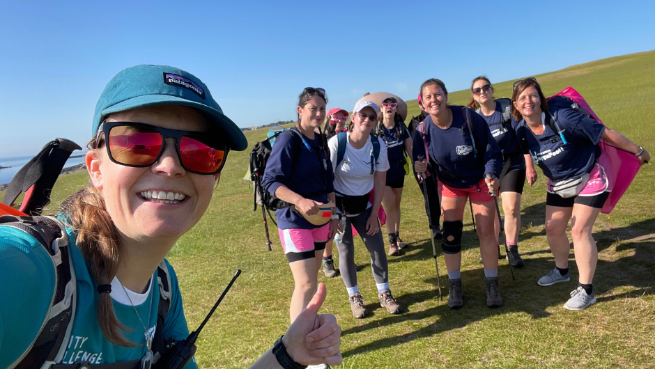 A group of female hikers smiling for a selfie on a sunny UK trek.