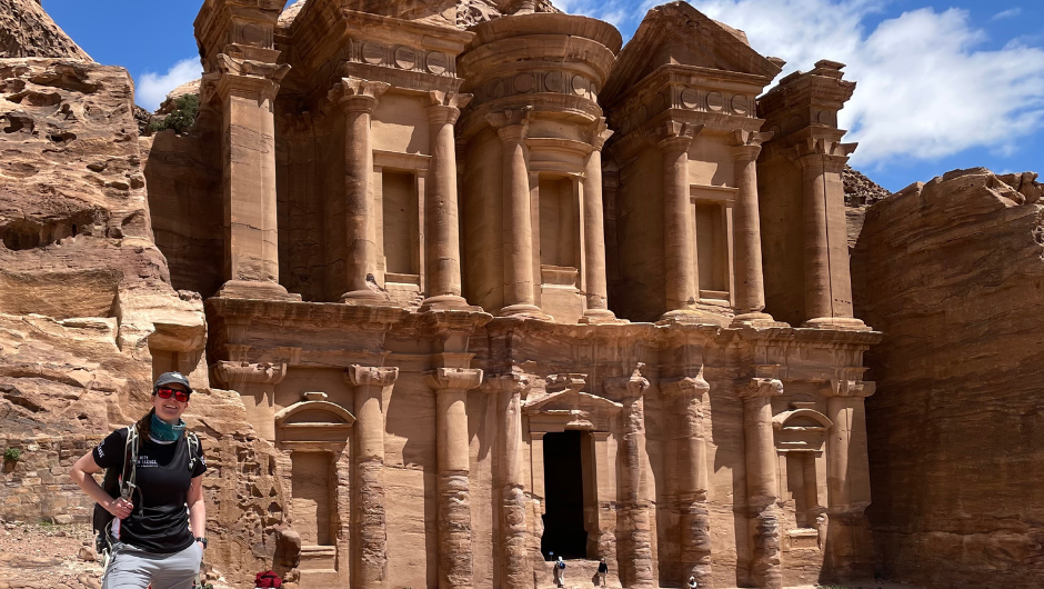 A trekker smiling in front of the Monastery in Petra, Jordan.