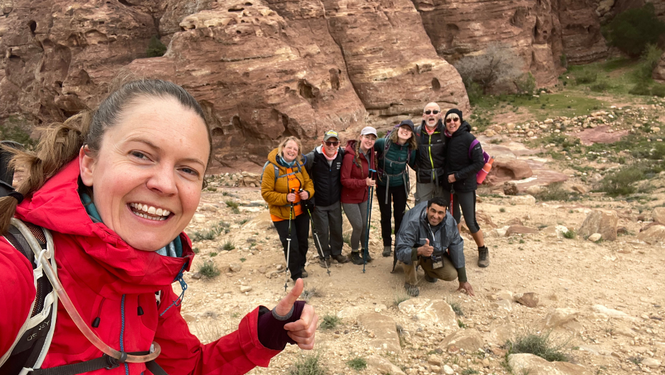 A group of hikers smiling for a selfie in a rocky area.