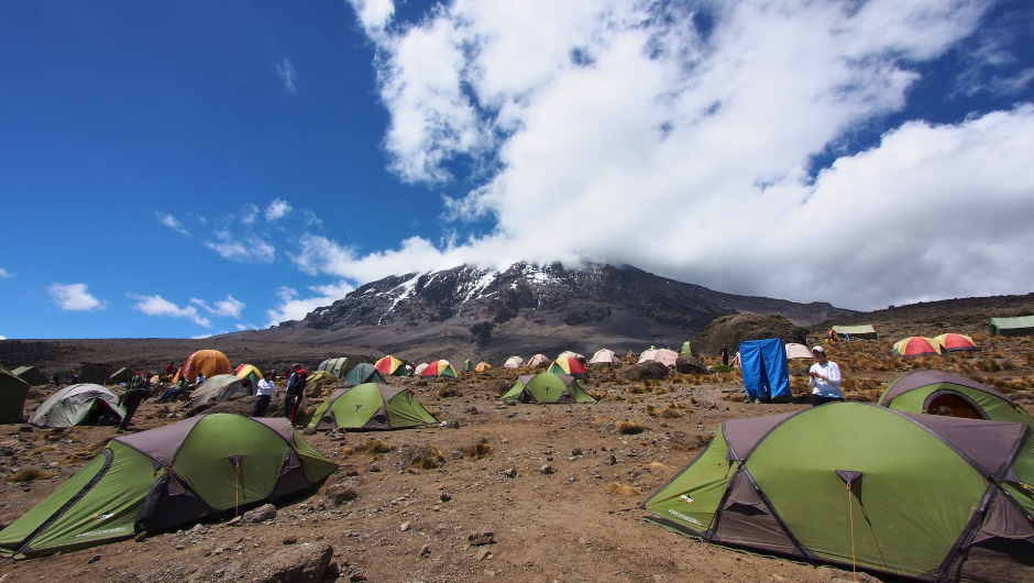 A campsite of tents at the base of Mount Kilimanjaro.