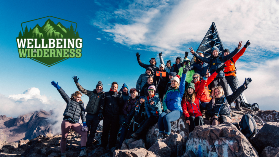 A group of trekkers celebrating with their hands in the air on the summit of Mount Toubkal, Morocco