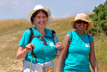 Charity challenge support: from booking to finish line. Two smiling women walking on a sunny south downs challenge