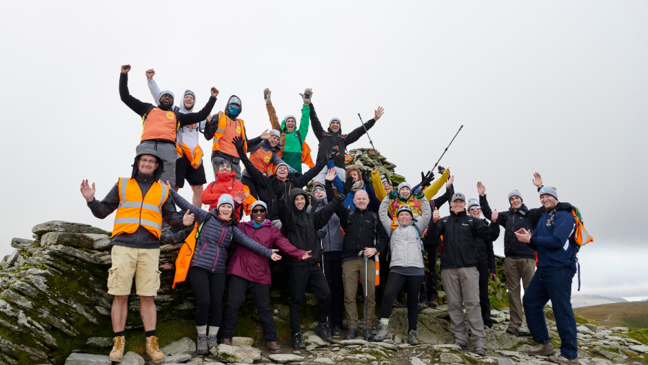 A group of trekkers celebrating at the summit of Old Man of Coniston in the Lake District.