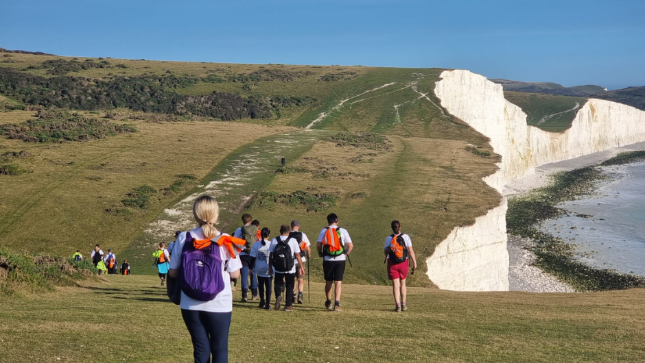 A group of trekkers walking down one of the undulating cliffs of the Seven Sisters, part of the South Downs way challenge.