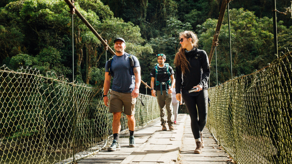 A small group of people walking across a bridge during their Trek to Machu Picchu challenge