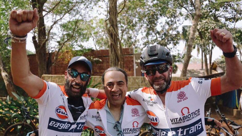 Three people dressed in cycling gear cheering.