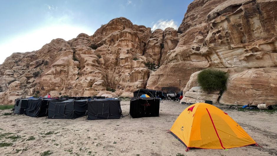 A campsite set up with tents, set against the rocky ridges of the Jordan desert.