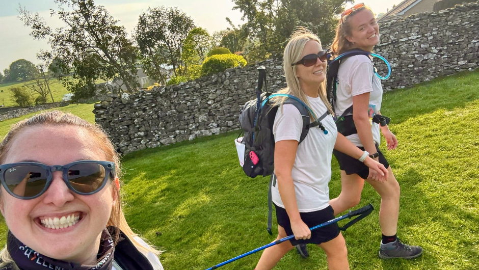 Three people walking together during a sunny UK trek.