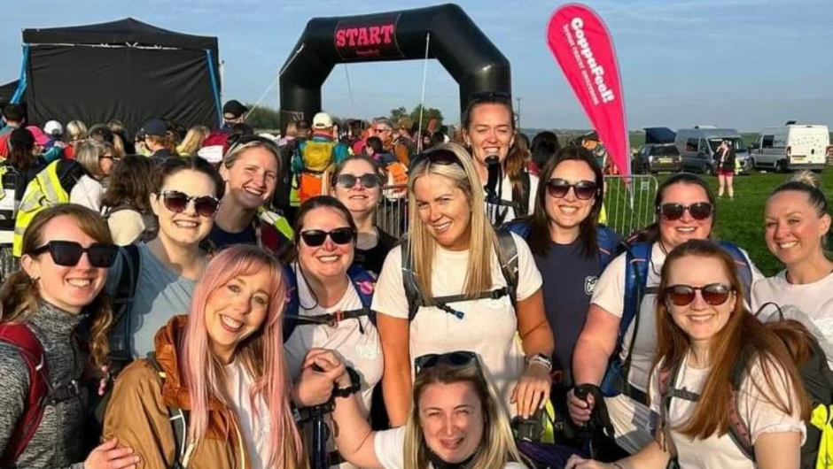 A group of people smiling at the start line of a sunny CoppaTrek! in the UK.