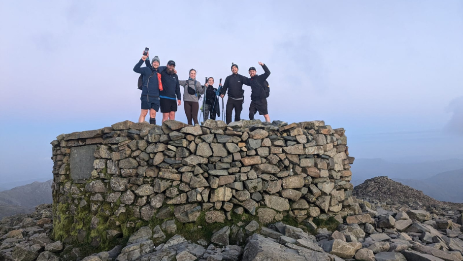 a group of trekkers celebrating at the summit of scafel pike during the national three peaks challenge