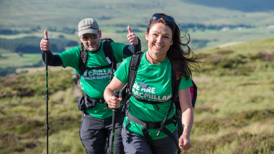 two smiling trekkers wearing green macmillan tshirts during their charity hike