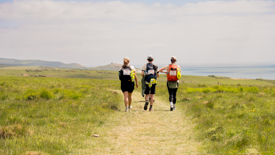 Three people trekking together on the South Downs Challenge with Charity Challenge.