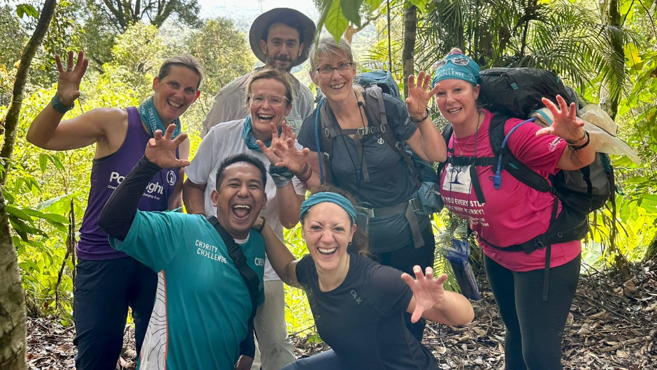 A happy group of Charity Challenge trekkers and guides, smiling and doing a 'roar' sign with their hands.