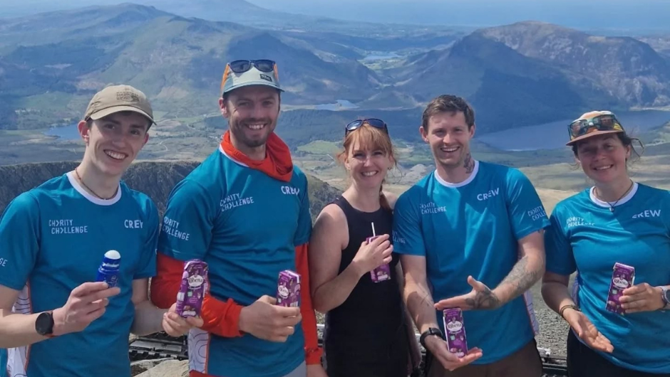 A group of Charity Challenge leaders smiling together at the top of Snowdon.