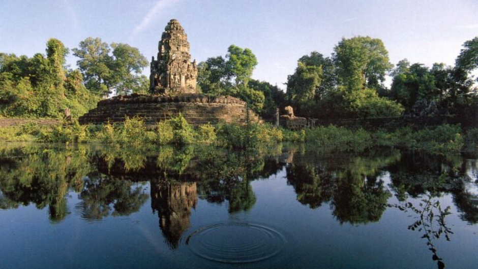 an ancient south east Asian temple, set against lush rainforest the bank of a river.