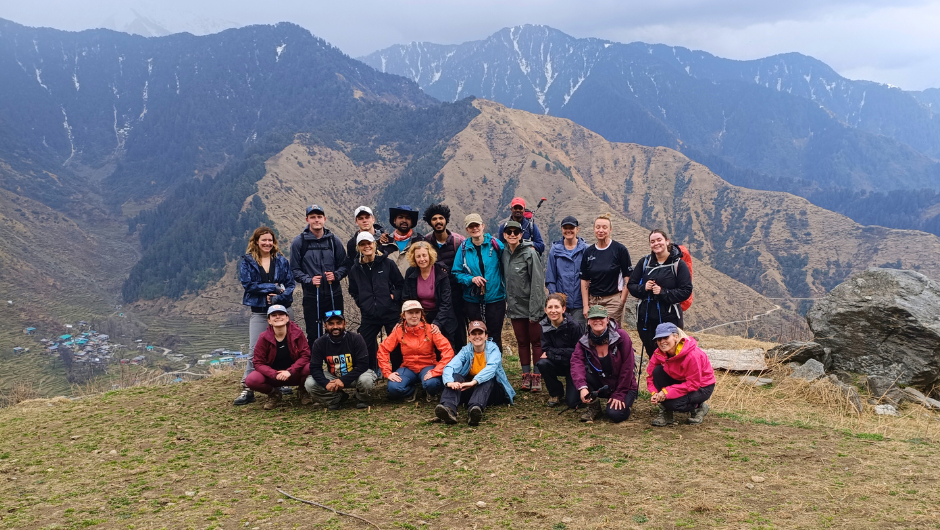 The bowelbabe fund himlayan trek challengers wearing rain jackets and smiling in front of a Himalayan mountain range.