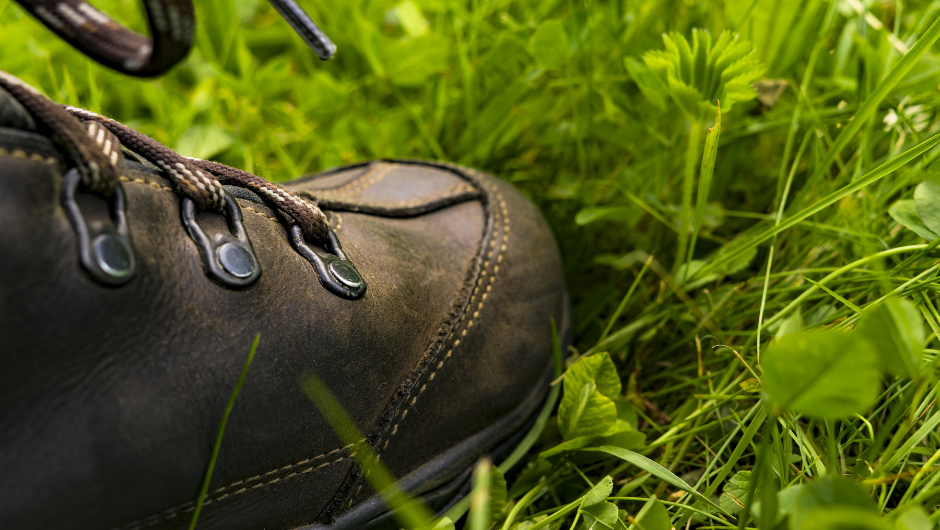 a close up of a walking boot in grass, highlighting the laces.