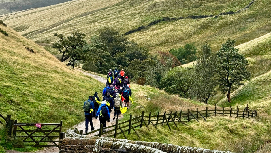 A group of trekkers hiking through a green path in the peak district