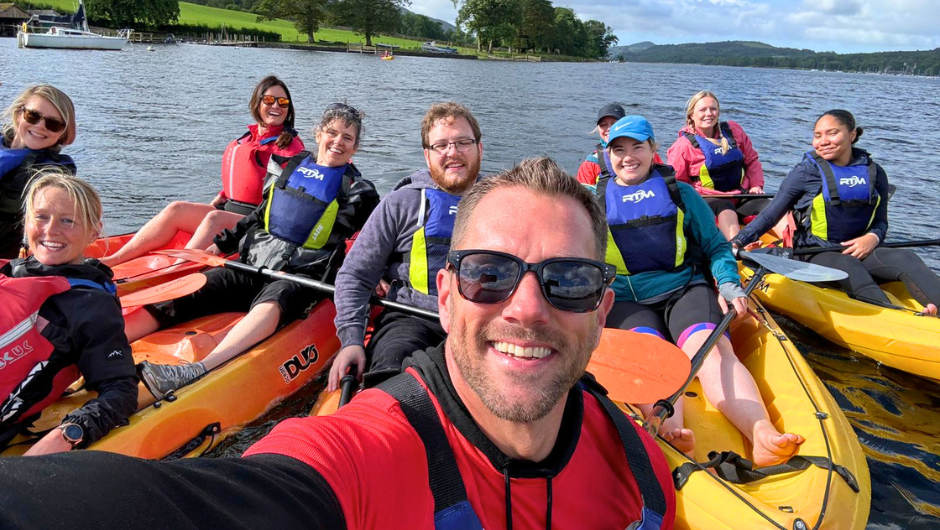 a person taking a selfie with a group of kayakers in a lake