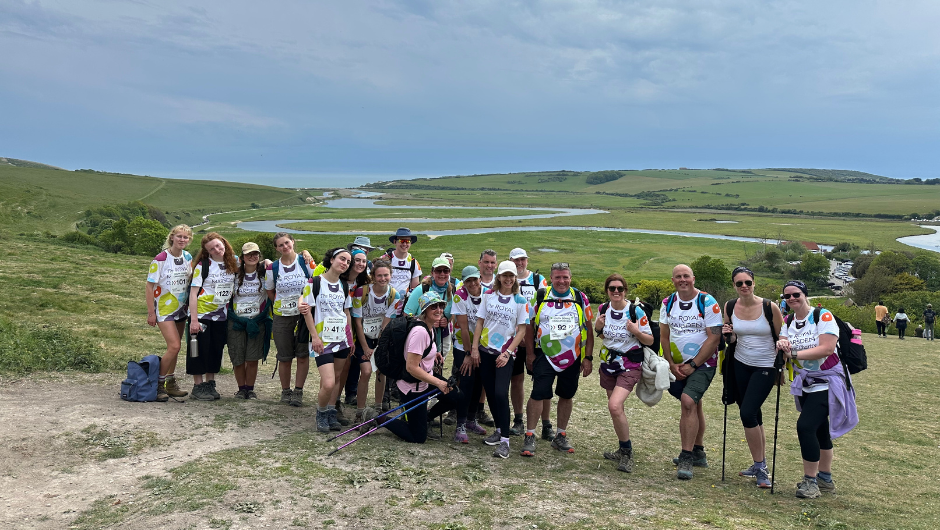 The royal marsden cancer charity supporters wearing royal marsden cancer charity t-shirts, stood in front of a winding river that heads out to sea.