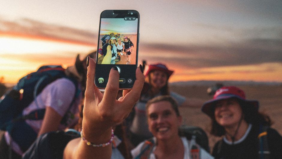 a group of people smiling for a mobile phone selfie during their sahara desert trek challenge