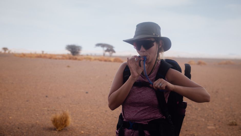a trekker in the sahara using their water bladder to sip water