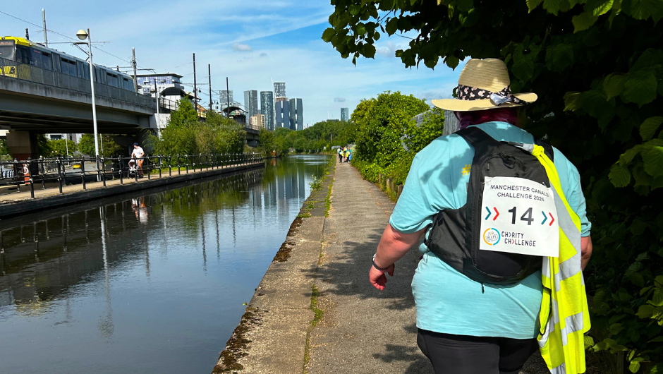 a person walking along a section of the Manchester canals, on a sunny day