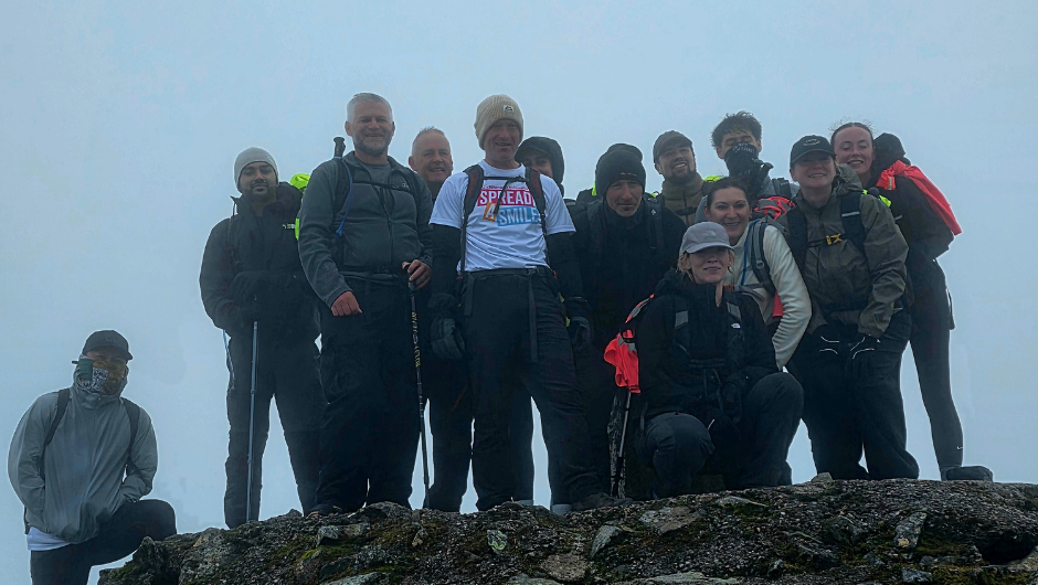 trekkers dressed in rain coats at the summit of a rainy mountain