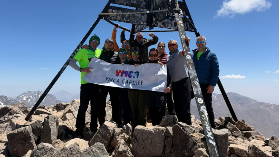 ymca cardiff mount toubkal trek challengers holding up their charity logo banner at the summit of mount toubkal