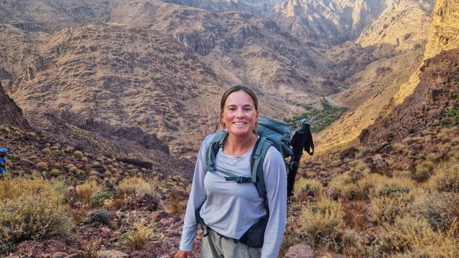 Nicki Couston, Operations Manager at Charity Challenge, smiling as she treks up a mountainous valley path.
