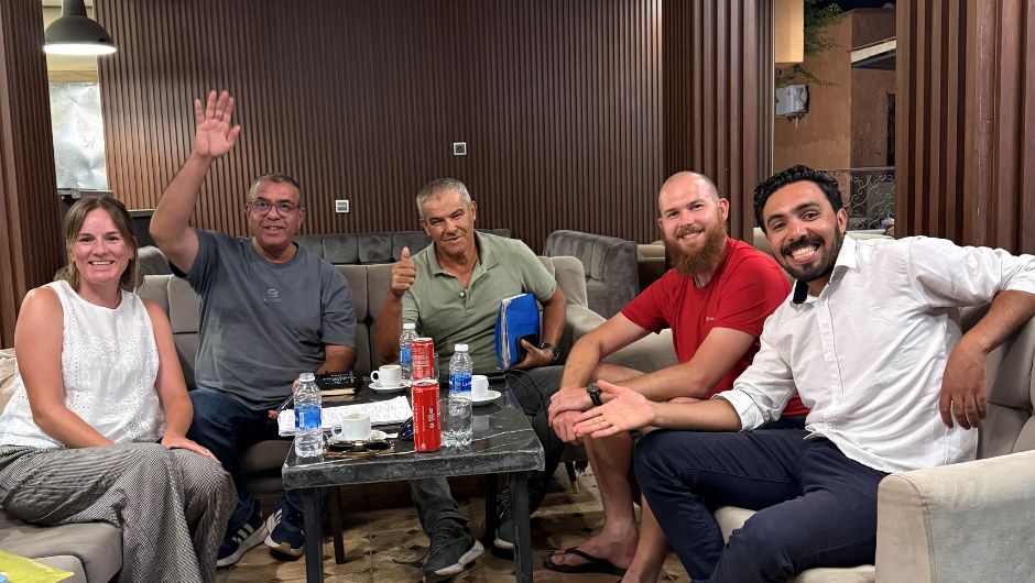 A group of people sitting around a table and smiling for the camera.