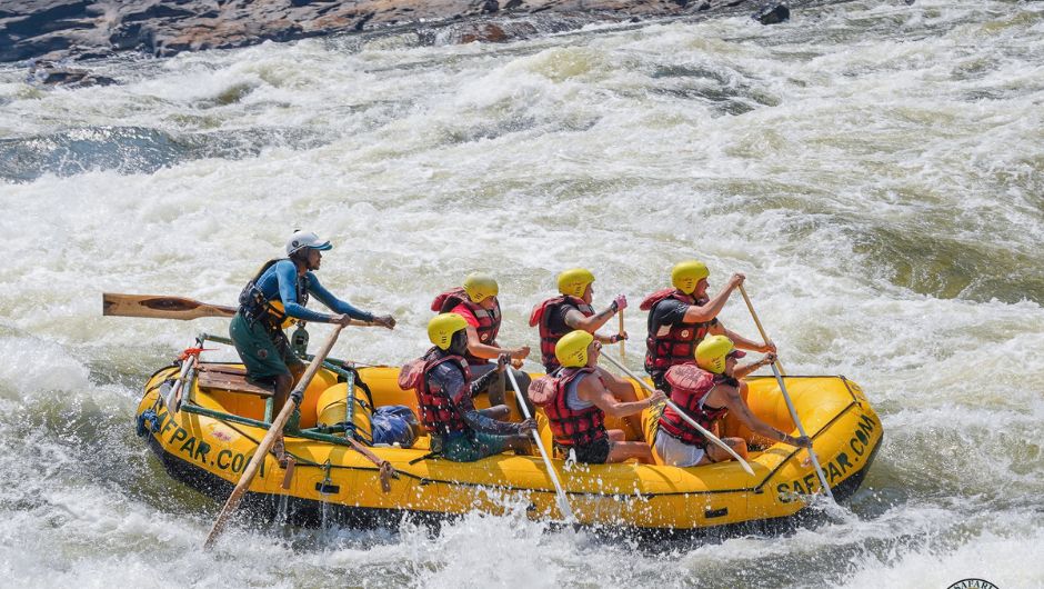 A group of people rafting through white water rapids during their Zambezi River Challenge.